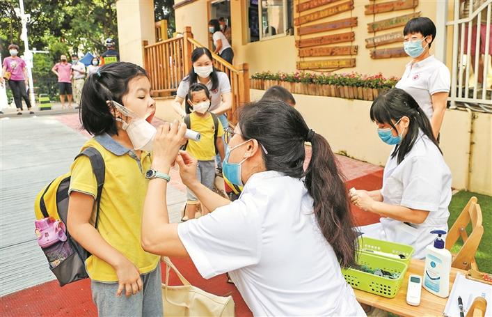 "南山区教育幼儿园门外,两个刚排进队伍等待入园的孩子热情地打起招呼